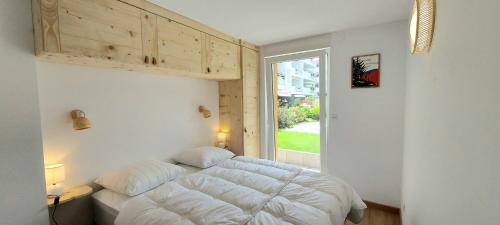 een slaapkamer met een wit bed en een raam bij Le Flocon du bord du lac in Gérardmer