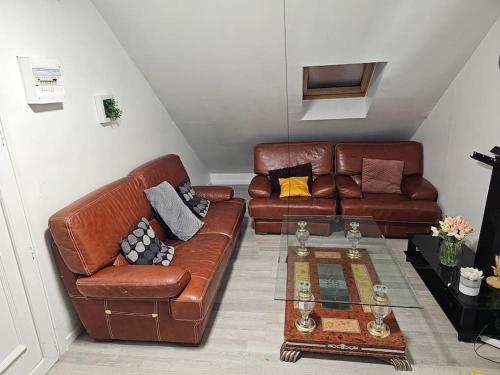 ein Wohnzimmer mit zwei braunen Ledersofas und einem Tisch in der Unterkunft Appartement meublé , 1 chambre in Magnanville