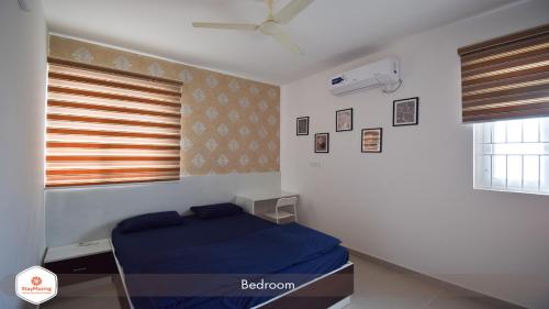 a bedroom with a blue bed and a window at StayMazing Manyata-1BHK Boutique AC Apartments -Couple Friendly in Bangalore