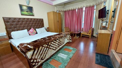 a bedroom with a large bed and a television at Hotel Jubilant Manali in Manāli