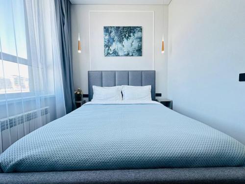 1 dormitorio con 1 cama grande con sábanas blancas en Кок Жайлау apartament, en Astana