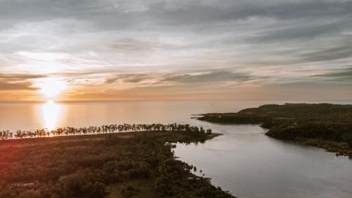 an island in the water with the sunset in the background at FireFly Querim in Querim