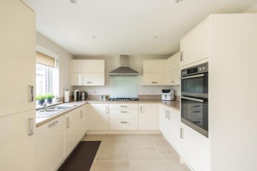 uma cozinha com armários brancos e um lavatório em Luxury Detached Home em Edimburgo