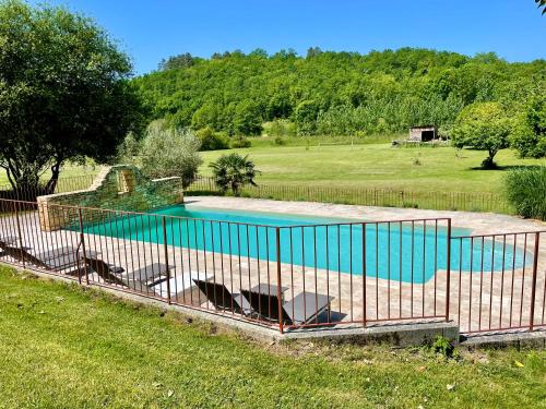 a fence around a swimming pool in a yard at Le Moulin Aux Ans in Archignac