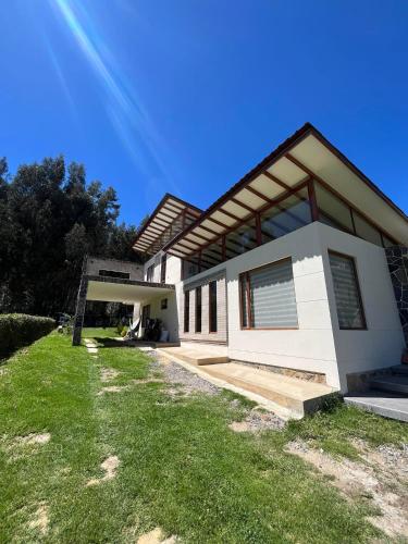 a white house with a grassy yard in front of it at Casa de Campo Moderna Ubaté - Sector La Laja in Ubaté