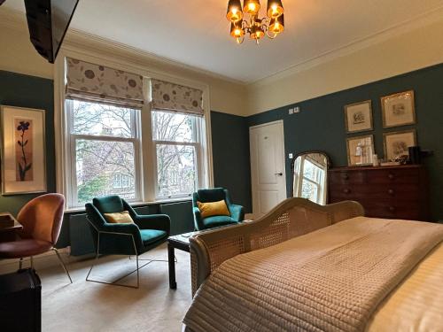 een slaapkamer met een bed, 2 stoelen en een spiegel bij Baytree House in Harrogate