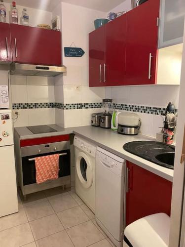 - une cuisine avec des placards rouges et un lave-linge dans l'établissement Appartement Stade de France, à Saint-Denis