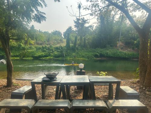 a picnic table next to a river with a boat at ชลลดา ริเวอร์ โฮมสเตย์ แก่งกระจาน in Ban Wang Malako