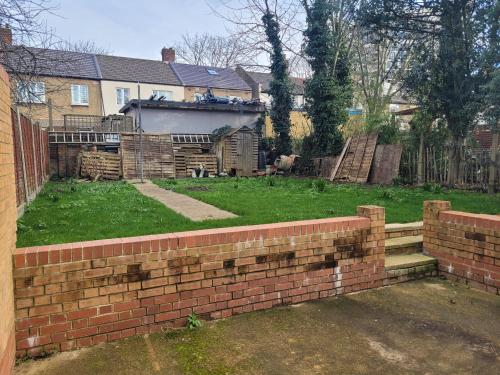 a yard with a brick wall in front of a house at Lovely 2-Bed fully refurbished House in London in London