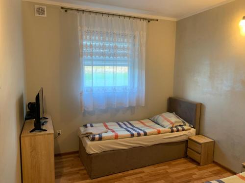 a small bedroom with a bed and a window at Zajazd Jagoda Pokoje i Restauracja 