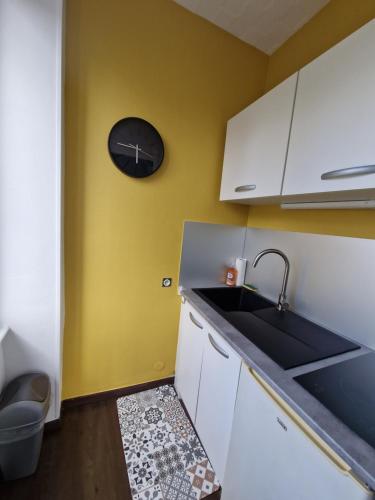 une cuisine avec un évier et une horloge murale dans l'établissement Studio proche rectorat et théâtre de l'union, à Limoges