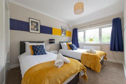2 Betten in einem Zimmer mit blauen und gelben Vorhängen in der Unterkunft The Shield in Chatham