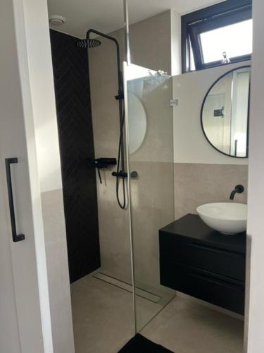 een badkamer met een glazen douche en een wastafel bij Veldt's huisje in Limmen