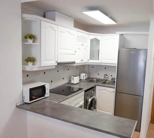 a kitchen with white cabinets and a stainless steel refrigerator at Lemon Apartment - Aquamarina Cabo Roig in Playas de Orihuela