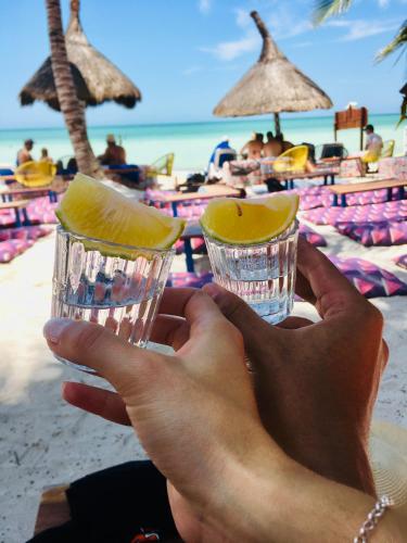 une personne tenant deux verres à boire sur la plage dans l'établissement PDC HOTELS, à Playa del Carmen