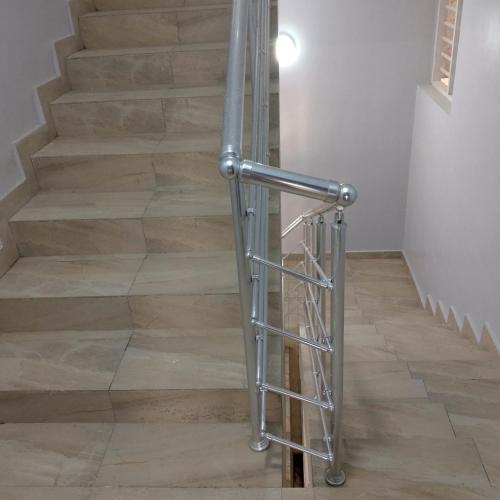 a staircase with a metal handrail and wooden floors at Coin nickel in Cotonou