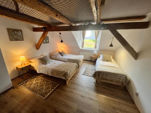 an attic room with two beds and a window at Dobrze Mi Tu-KIKITY in Kikity