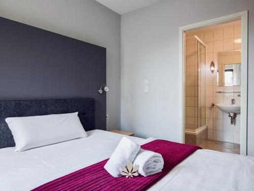 ein Schlafzimmer mit einem Bett mit Handtüchern und einer Dusche in der Unterkunft Hotel Kastanienbaum in Herzogenaurach