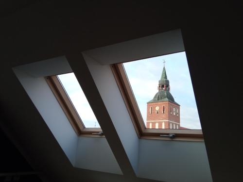 a view of a clock tower from a window at Apartament Warmiński - Old Town in Biskupiec
