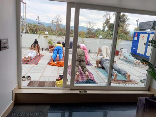 a group of people performing a yoga pose in a window at Hotel Mahadev Rishikesh in Rishīkesh