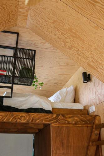 Bett in einem Zimmer mit Holzdecke in der Unterkunft Ekko tiny house in Philippeville