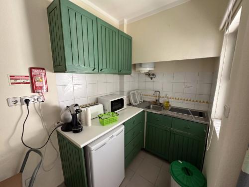 a small kitchen with green cabinets and a microwave at Cozy apartment in Praia da Rocha in Portimão