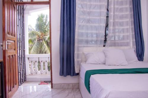 - une chambre avec un lit et une fenêtre avec un palmier dans l'établissement Mtwapa Musical Utopia apartment, à Mombasa