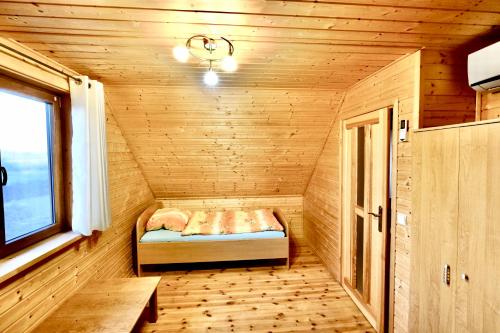 a small room with a bed in a wooden cabin at Domek Pod Lasem in Pozezdrze