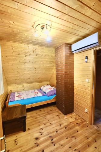 a small room with a bed in a wooden cabin at Domek Pod Lasem in Pozezdrze