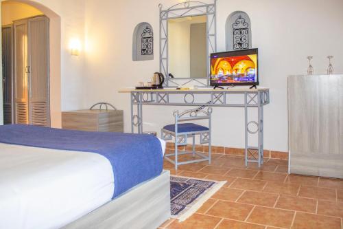 Protels Beach Club & SPA في مرسى علم: غرفة نوم بسرير وطاولة مع تلفزيون