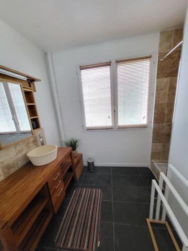 uma casa de banho com um lavatório e 2 janelas em Maison avec jardin à proximité de la plage et du canal du Midi pour 6 personnes em Portiragnes