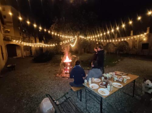 a group of people sitting around a table with a fire at Casa Valduggia in Valduggia