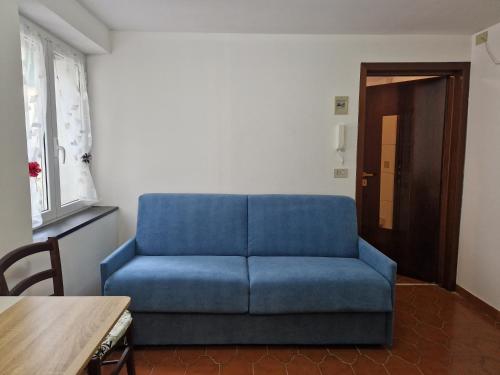 Sofá azul en la sala de estar con mesa en Vico 2 monolocale en Albissola Marina