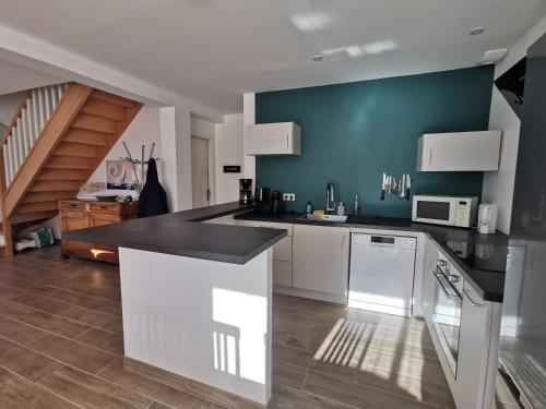 une cuisine avec des armoires blanches et un comptoir noir dans l'établissement Aux portes de Chausey, à Saint-Pair-sur-Mer