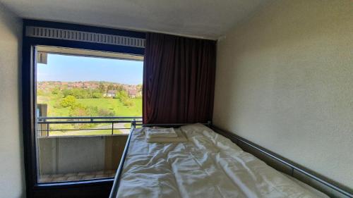 ein Bett in einem Zimmer mit einem großen Fenster in der Unterkunft Hohegeiß Ferienwohunung - 14ter Etage mit Blick in Braunlage