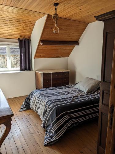 une chambre avec un lit et un plafond en bois dans l'établissement La maison du bas, à Crasville
