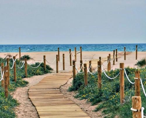 een houten pad dat leidt naar een strand met de oceaan bij UIM Mediterraneo Cendoya 4 Wifi in Puerto de Sagunto