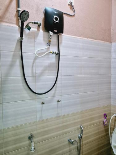 a shower in a bathroom with a blow dryer on the wall at Teratak Che Esah Guest House FREE WIFI NETFLIX in Pasir Mas