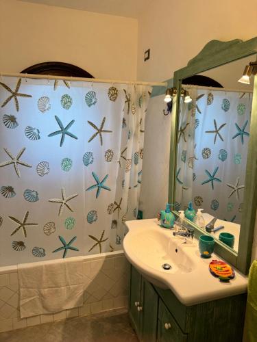 a bathroom with a sink and a shower curtain at Villa Holiday Park Stintino in Stintino
