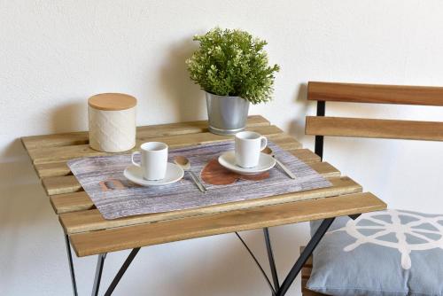 un tavolo di legno con tazze e piattini sopra di Casa vacanza "Glicine" Taormina-Trappitello a Taormina