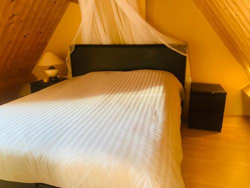 a bedroom with a bed with a white comforter at Topzomer in Sleat in Sloten