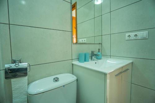 a bathroom with a toilet and a sink and a mirror at Bravo Hills Apartment in Ciudad Quesada