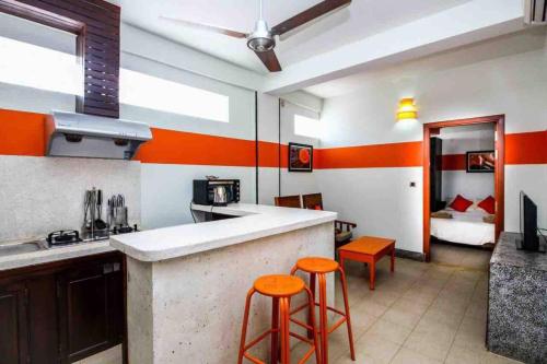 CHILCHILL Elite Residences BKK2 في بنوم بنه: مطبخ بجدران برتقالية وبيضاء وكراسي برتقالية