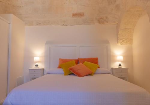 um quarto com uma cama branca e almofadas coloridas em Masseria Carperi in the heart of Valle d'Itria em Cisternino
