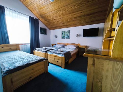 ein Hotelzimmer mit zwei Betten und einem Fernseher in der Unterkunft Mikolaj in Białogóra