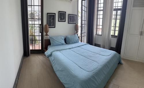 a bedroom with a bed with blue sheets and windows at CHILCHILL Elite Residences BKK2 in Phnom Penh