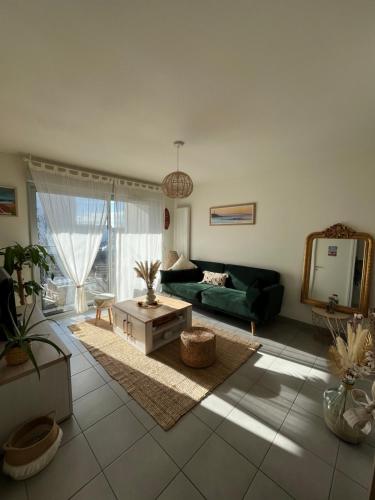 een woonkamer met een groene bank en een spiegel bij Appartement T2 cosy et calme in Bayonne
