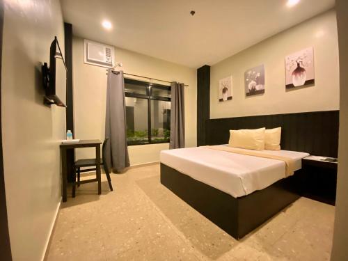 a bedroom with a bed and a desk and a window at Rudolfo Suites in Roxas City