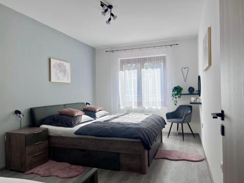 a bedroom with a bed and a chair and a window at Apartmán Lakeside in Český Krumlov