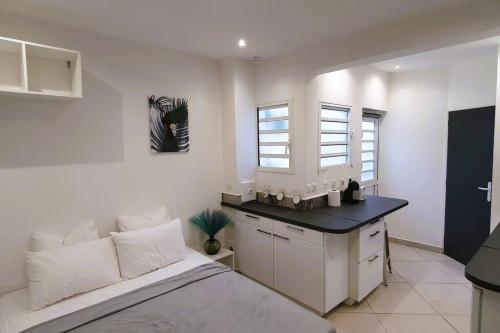 a bedroom with a bed and a kitchen with windows at Studio pour 2 personnes proche de l'hôpital et du jardin de l'état in Saint-Denis